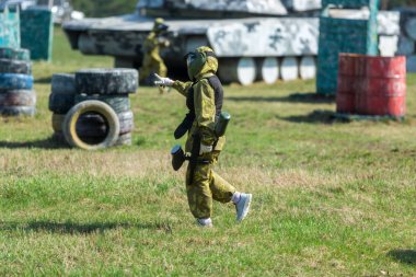 Kamuflaj çocukta bir paintball silahı bir yandan ve koruyucu kask, sahada ayakta tutar. aktif spor yaşam tarzı kavramı 