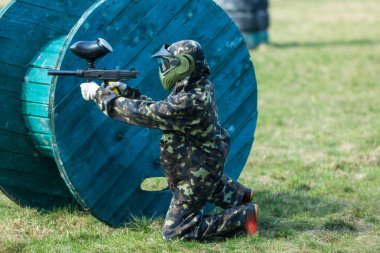 Kamuflaj çocukta bir paintball silahı bir yandan ve koruyucu kask, sahada ayakta tutar. spor yaşam tarzı kavramı 