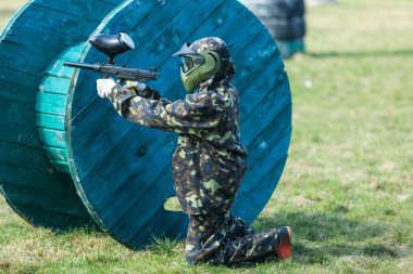 Kamuflaj çocukta bir paintball silahı bir yandan ve koruyucu kask, sahada ayakta tutar. spor yaşam tarzı kavramı 