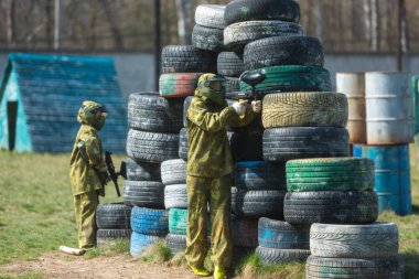 Kamuflaj çocukta bir paintball silahı bir yandan ve koruyucu kask, sahada ayakta tutar. spor yaşam tarzı kavramı 