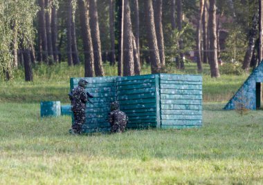 Kamuflaj elbiseli çocuk onun paintball silahı ile paintball sahada duruyor ve dümdüz görünüyor. takım çalışması, spor yaşam tarzı