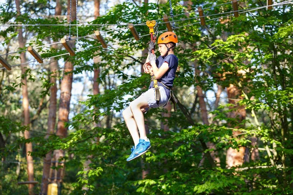 穿着蓝色 T恤和头盔的年轻男孩 在冒险公园玩 拿着绳子 爬上木梯 积极的生活方式概念 — 图库照片