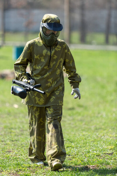 Мальчик в камуфляжном костюме стоит на пейнтбольном поле с пистолетом и смотрит прямо перед собой. командная работа, спортивный образ жизни

