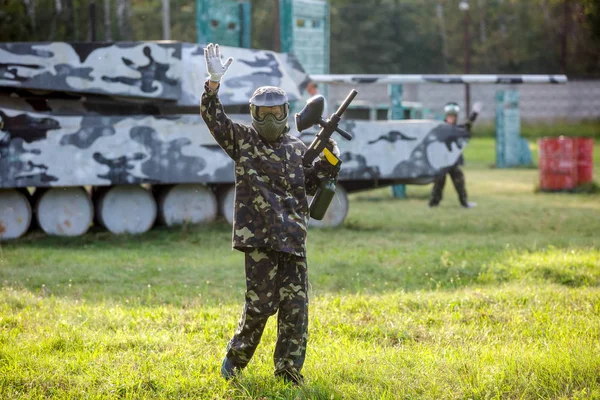 sporty boy in camouflage form with black gun plays paintball on the field. Active sport life, hobby concept