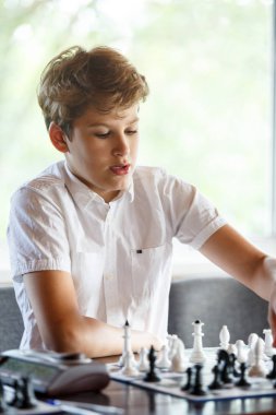 şirin, akıllı, 11 beyaz gömlek eski çocuk sınıfta oturuyor ve satranç satranç tahtası üzerinde çalış yıl. Eğitim, ders, hobi, eğitim kavramı. fikri oyunu.