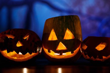 korkunç yüzler ve mum turuncu Kabak Koyu mavi arka plan önünde masada yatıyor. Cadılar Bayramı kutlama kavramı