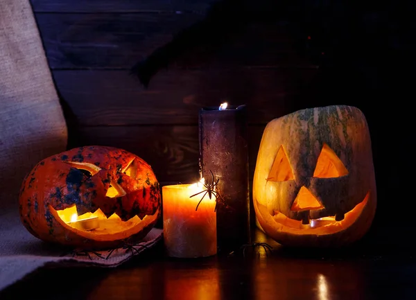 orange pumpkins with scary faces and candles lies on the table in front of dark blue background. Halloween celebration concept