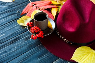 Şapka rengi kırmızı, sarı sonbahar yaprakları ve kahve ya da çay gri bir ahşap zemin üzerine Bordo veya marsala. Moda trend sonbahar, kış, coziness, kavramı konfor