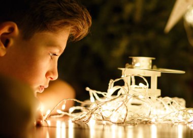 Işıklar ve rüyalar sevimli genç çocuk saatleri bir dilek evde yılbaşı için yapar. Noel ve yeni yıl kutlama, ev dekorasyon konsepti