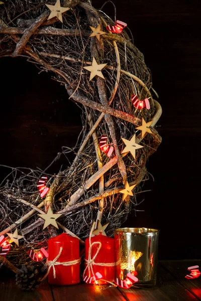 red candles with fire in front of New year wreath with lights. Christmas and New Year celebration, handmade concept. holiday and celebration concept for postcard or invitation.