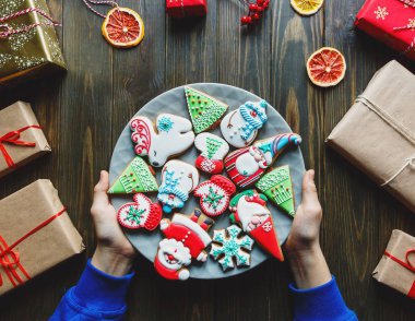 Çocuklar el yapımı gingerbreads tam plaka ile el: Noel Baba, kar tanesi, geyik, çam ağacı, hediyeler ile koyu ahşap arka plan formlarında kardan adam. Noel ve yılbaşı dekorasyon konsepti