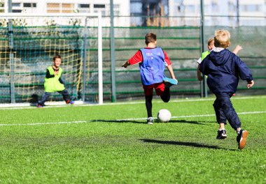 çocuklar içinde kırmızı ve mavi, yeşil üniformalar yeşil çimenlerin üzerinde futbol takımı ile oynamak. Takım oyunu, eğitim, aktif yaşam tarzı, hobi, spor çocuklar konsepti için