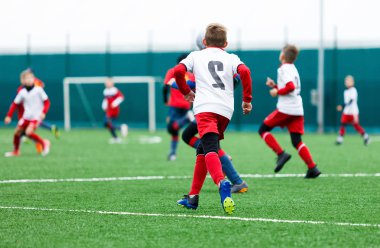 futbol takımları - kırmızı, mavi, Beyaz üniformalı erkekler yeşil sahada futbol oynamak. Çocuklar top sürme. top sürme becerileri. Takım oyunu, eğitim, aktif yaşam tarzı, hobi, spor çocuklar konsepti için