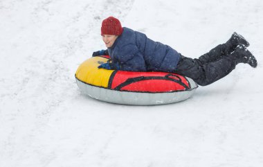 Çocuk mavi ceket ve kar tüp kırmızı şapka. Çocuk bir boru sürme. Kış eğlence, etkinlikler. aktif spor, yaşam biçimi