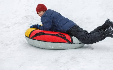 Çocuk mavi ceket ve kar tüp kırmızı şapka. Çocuk bir boru sürme. Kış eğlence, etkinlikler. aktif spor, yaşam biçimi
