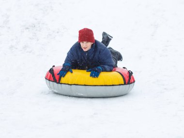 Çocuk mavi ceket ve kar tüp kırmızı şapka. Çocuk bir boru sürme. Kış eğlence, etkinlikler. aktif spor, yaşam biçimi