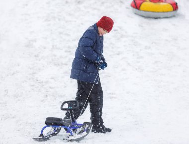 Çocuk mavi ceket ve kar tüp kırmızı şapka. Çocuk bir boru sürme. Kış eğlence, etkinlikler. aktif spor, yaşam biçimi