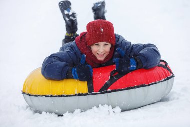 Çocuk mavi ceket ve kar tüp kırmızı şapka. Çocuk bir boru sürme. Kış eğlence, etkinlikler. aktif spor, yaşam biçimi