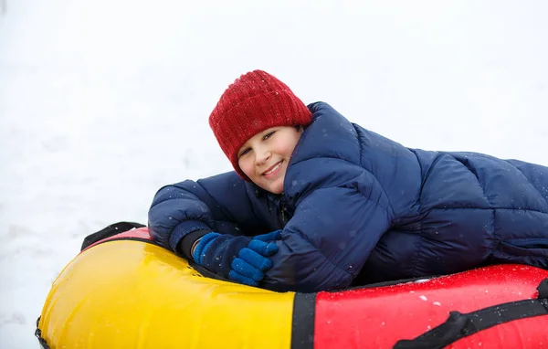 蓝色夹克和红帽的孩子在雪管乐趣 男孩在骑油管 冬季娱乐活动 积极的运动 生活方式 — 图库照片