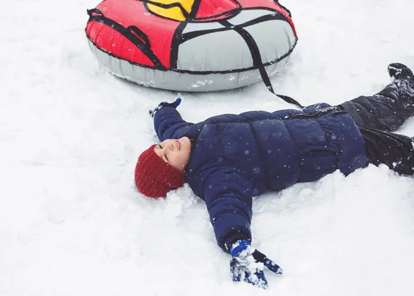 蓝色夹克和红帽的孩子在雪管乐趣 男孩在骑油管 冬季娱乐活动 积极的运动 生活方式 — 图库照片