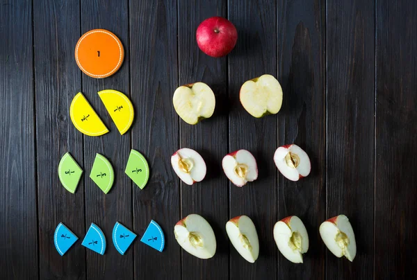 renkli matematik kesirler ve elma kahverengi ahşap arka plan veya tablo üzerinde bir örnek olarak. çocuklar için ilginç matematik. Eğitim, okul kavramı. Geometri ve matematik malzemeleri.