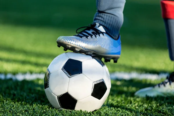 Klasik siyah ve beyaz futbol topu alan ve spor ayakkabılarla bacağından yeşil çimenlerin üzerinde. Eğitim, maç, hobi kavramı. kopya alanı ile 