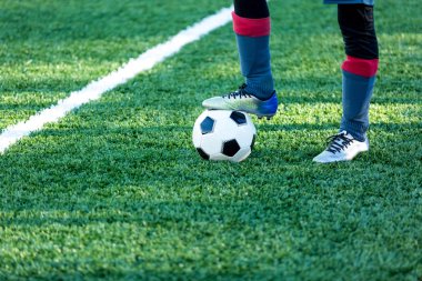 Klasik siyah ve beyaz futbol topu alan ve spor ayakkabılarla bacağından yeşil çimenlerin üzerinde. Eğitim, maç, hobi kavramı. kopya alanı ile 