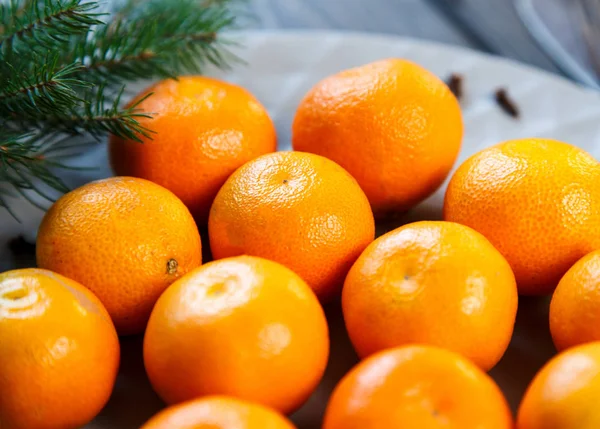 みかんの明るいオレンジ色の緑と熟した灰色プレート木製テーブルの上のモミの枝を残します デザートはクリスマスとお正月のテーブルの設定 — ストック写真