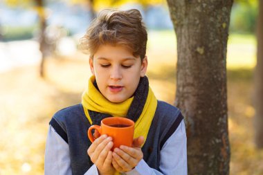 Çocuk turuncu fincan düşen yapraklar arka plan üzerinde elinde tutar. Sonbahar ruh hali güzel bir gün. Natürmort altın sonbaharda. Parlak sonbahar resim.  