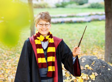 gözlüklü çocuk Sonbahar Park altın yaprakları ile standları, değnek elinde tutuyor, siyah takım elbise ve çizgili eşarp takıyor. Harry Potter film tarzı, Halloween kılık