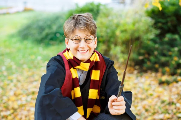 Kiev/Ukrayna - 21 Ekim 2018: çocuk gözlük standları altın yaprakları, onun elinde tutan kitap ile sonbahar park giydiği siyah takım elbise ve çizgili eşarp. Harry Potter stil, Cadılar Bayramı Kostüm, cosplay