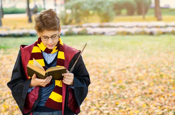 gözlüklü çocuk sonbahar parkta duruyor, değnek elinde tutar, kitap, siyah takım elbise ve çizgili eşarp takıyor. Cadılar Bayramı Kostüm, cosplay