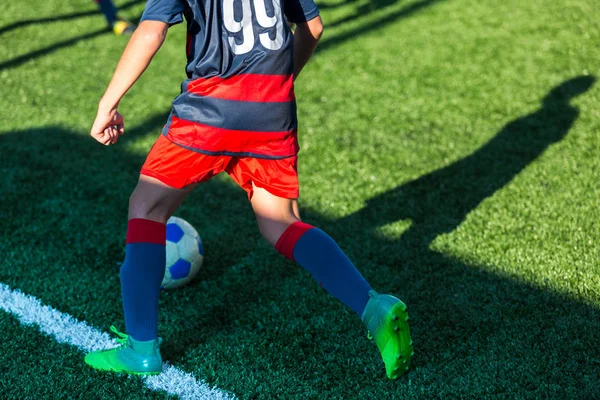 football teams - boys in red, blue, white sportswear play soccer on the green field. boys dribbling. dribbling skills. Team game, training, active lifestyle, hobby, sport for kids concept