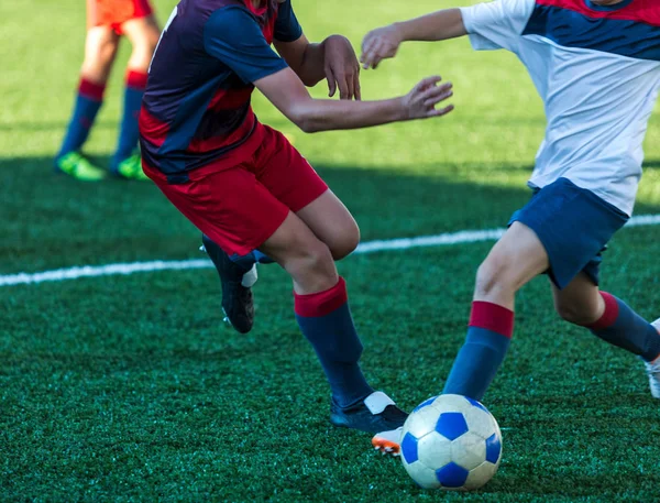 football teams - boys in red, blue, white sportswear play soccer on the green field. boys dribbling. dribbling skills. Team game, training, active lifestyle, hobby, sport for kids concept