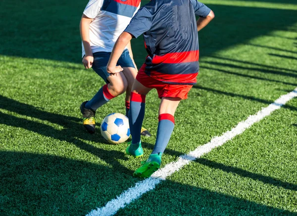 football teams - boys in red, blue, white sportswear play soccer on the green field. boys dribbling. dribbling skills. Team game, training, active lifestyle, hobby, sport for kids concept