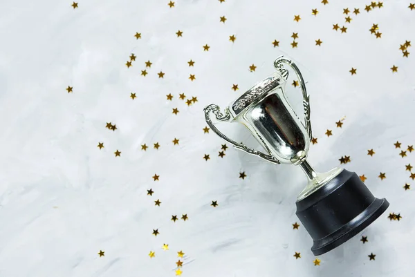 Golden trophy and stars confetti on gray cement background. sport achievement, success concept. Gold trophy as a leader. Business successful.