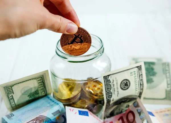 kadının el altın bitcoin arasında gerçek para arka plan cam kavanoza koyar. Kripto para birimi, tasarruf, yatırım, risk kavramı birikimi