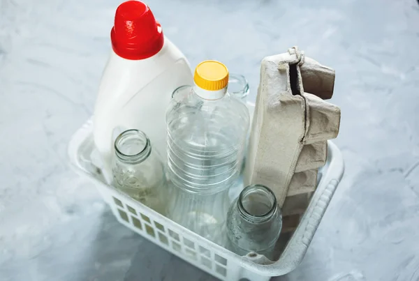 different wastes ready for recycling in white basket. Plastic bottles, glass, egg tray. Social responsibility, ecology care, recycling at home concept