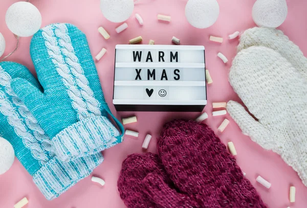 Warm, cozy knitted winter clothing, lightbox on  pastel pink background. Christmas concept flat lay. warm xmas title. winter fashion composition. Top view