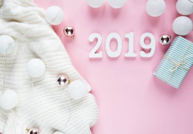 Noel kavramı düz yatıyordu. Beyaz kış giyim, 2019 numarası ve Noel süslemeleri pembe arka plan karede sıcak, rahat