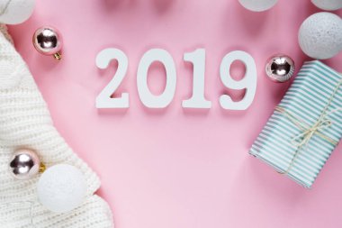 Noel kavramı düz yatıyordu. Beyaz kış giyim, 2019 numarası ve Noel süslemeleri pembe arka plan karede sıcak, rahat