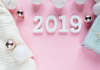 Noel kavramı düz yatıyordu. Beyaz kış giyim, 2019 numarası ve Noel süslemeleri pembe arka plan karede sıcak, rahat