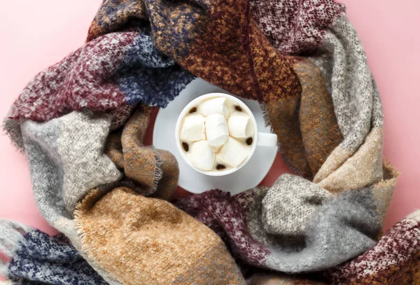 Warm, cozy winter clothing, scarf and cup of coffee with white marshmallow as frame on pastel pink background. Christmas concept flat lay. hello winter title