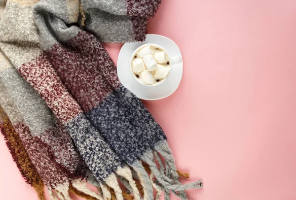 Warm, cozy winter clothing, scarf and cup of coffee with white marshmallow as frame on pastel pink background. Christmas concept flat lay. hello winter