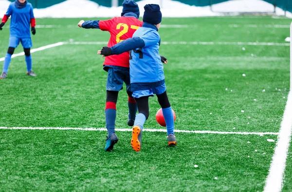 Two young Footballers running,dribble and competing for ball. Junior football match competition. Winter activities, soccer game, training concept