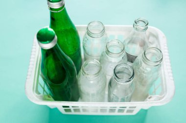 farklı cam şişe hazır yeşil zemin üzerine beyaz sepet içinde geri dönüşüm için harcar. Sosyal sorumluluk, ekoloji bakımı, evde kavramı geri dönüşüm