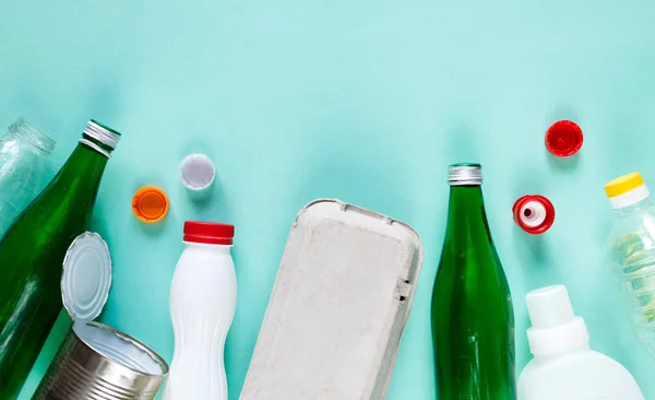 different wastes ready for recycling in white basket on green background. Plastic bottles, glass, egg tray. Social responsibility, ecology care, recycling at home concept