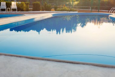 Modern yüzme havuzu görünümünü günbatımında otel kapatın. Yüzeyde güneş ışığı. Yaz tatili, tatil, sakin ol, yaz etkinlikleri kavramı