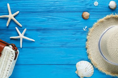 Mavi zemin üzerine beyaz rattan çanta, hasır şapka. Bambu trendy çanta, deniz yıldızı, kabukları. Yaz moda düz yatıyordu, tatil, seyahat kavramı. Kopya alanı ile üstten görünüm. 