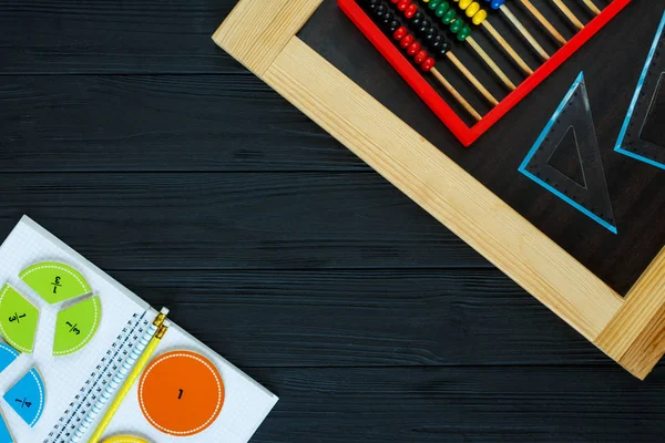 Colorful math fractions on dark wooden background or table. Interesting math for kids. Education, back to school concept. Geometry and mathematics materials. Mental math.